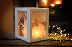 an old photo is lit up in front of a small box with string lights around it