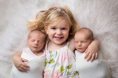 three little babies are laying next to each other on a fluffy white blanket and smiling at the camera