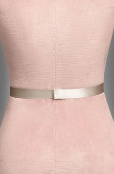 a woman in a pink dress with a silver belt on her waist and the back of her body