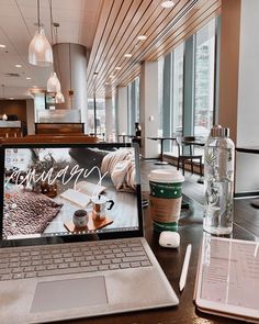 an open laptop computer sitting on top of a desk next to a cup of coffee