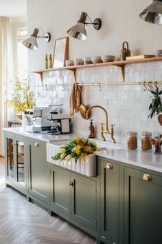 a kitchen with green cabinets and white tile backsplash, hanging lights above the sink