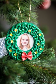 a christmas ornament hanging on a tree with a photo in the center and red bow