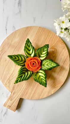 a wooden cutting board topped with cucumbers and flowers