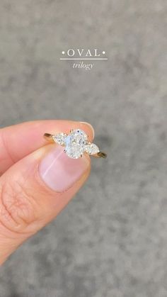 a woman's hand holding an engagement ring with two diamonds on it and the words oval