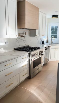 a kitchen with white cabinets and marble counter tops, stainless steel appliances and an oven