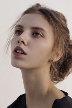 a close up of a person with a hair in a bun and wearing a black shirt