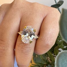 a woman's hand with a yellow and white diamond ring on top of her finger