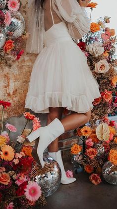 a woman in a white dress and high heeled boots is posing for the camera