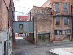 an old brick building with graffiti on it's side in the middle of town