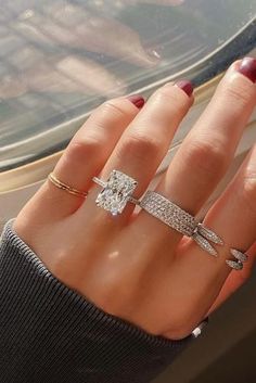 a woman's hand with three different rings on her fingers and one ring in the middle