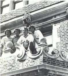 an old black and white photo of four people on the top of a building