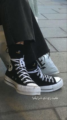 a person wearing black and white converse sneakers