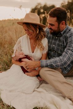 a man and woman sitting on the ground holding a baby