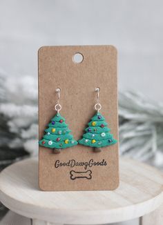 a pair of green christmas trees are on a small card with a dog bone in the background