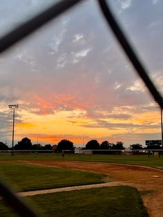 the sun is setting over a baseball field