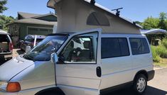 a van parked in front of a house with an awning on it's roof