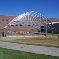 a large metal structure sitting on top of a grass covered field next to a building