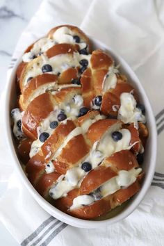 a white bowl filled with blueberries and cream cheese danish bread on top of a towel