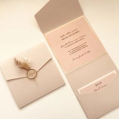 a wedding card and envelope with a feather quill on the front, sitting on a table