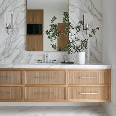 a bathroom with marble counter top and wooden cabinetry, along with a large mirror above the sink