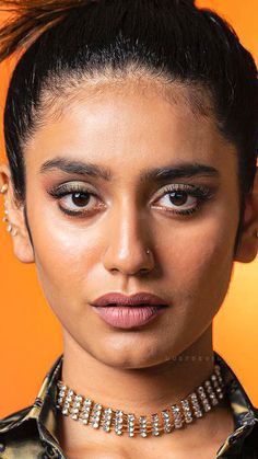 a close up of a person wearing a choker and pearls on her neck with an orange background