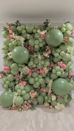 an arrangement of grapes and flowers is displayed on the wall in front of a window