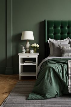 a bed with green headboard and pillows in a room that is painted dark green