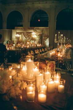 many lit candles are on the table in front of an audience at a formal event