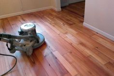 a floor scruber on the ground in a room with hard wood floors and white walls