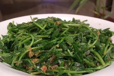 a white plate topped with green vegetables on top of a table