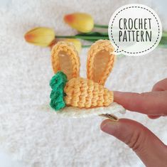 a crochet bunny sitting on top of a piece of paper next to flowers