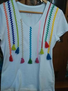 a white t - shirt with multi colored tassels hanging from it's chest