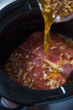 the meat is being poured into the slow cooker to make it look like it has been cooked