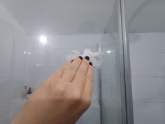 a woman's hand holding something in front of a shower