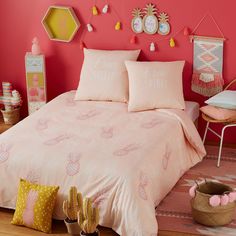 a bed with pink sheets and pillows in a room