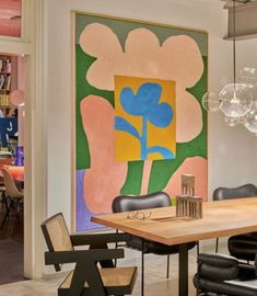 a dining room table with chairs and art on the wall