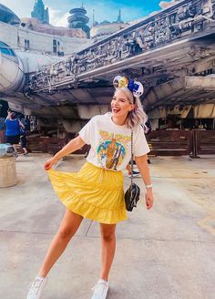 a woman in a yellow skirt is posing for a photo at the star wars theme park