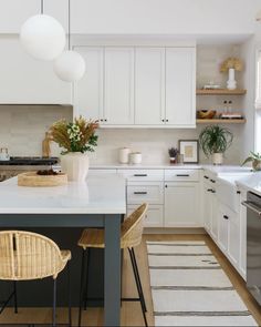 a kitchen with white cabinets and countertops has a black table in the foreground