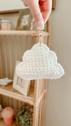 a person is holding a keychain with a crocheted cloud on it