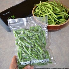 a bag of green beans sitting on top of a counter next to a bowl of beans