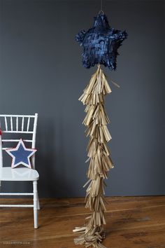 a tall wooden star hanging from the ceiling next to a white chair