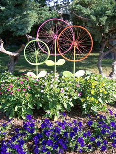 three metal garden art pieces sitting in the middle of flowers