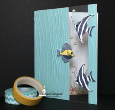 a card with some fish on it and a roll of tape in front of it