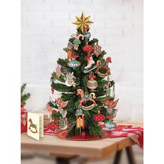 a small christmas tree on a table with ornaments around it and a card in the background