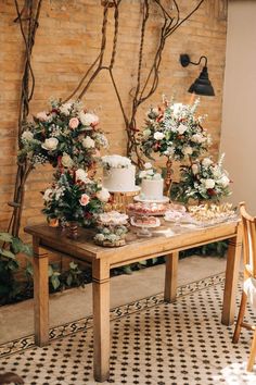 a table with cake and flowers on it in front of a brick wall at a wedding reception