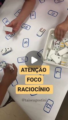 two children are playing with dominos on a white tablecloth that says atencao foco raciocino