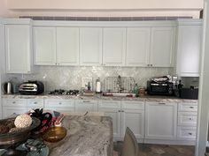 a kitchen with marble counter tops and white cabinets