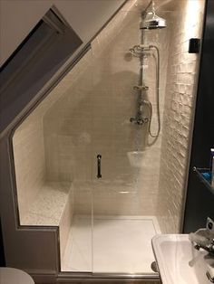 a walk in shower sitting next to a white sink under a faucet mounted on a wall