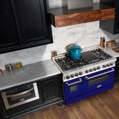 a blue stove top oven sitting inside of a kitchen next to black cabinets and counter tops