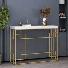 a white and gold console table next to a potted plant in a gray room